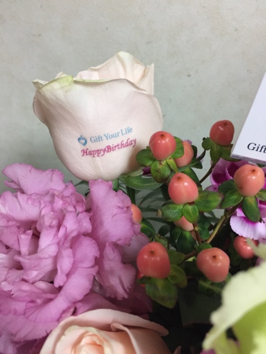 とある会社社員さんがお誕生日、との事で、社員一同さんから『Happy Birthday』フラワーアレンジのバラ1輪にのせたメッセージ