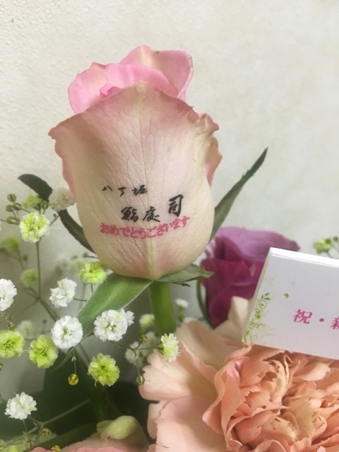 とあるお寿司屋さん開店のお祝いフラワーアレンジの中のバラ1輪に、お店のロゴとお祝いメッセージをのせました